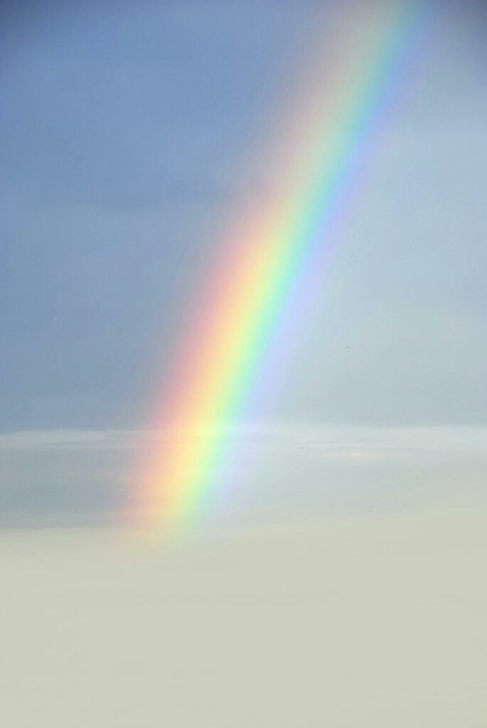 Beautiful rainbow emerging from clouds in a serene sky.